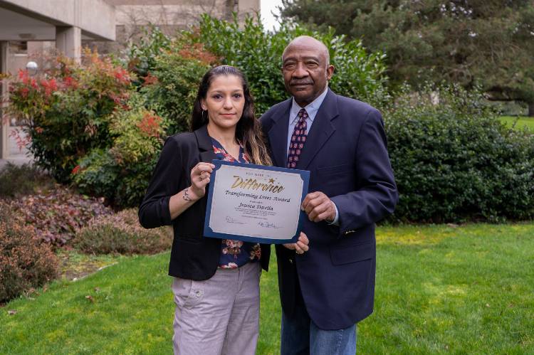 Jessica Davila and EC Board of Trustees Chair Wally Webster pose with award outside